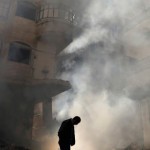 File photo of a man walking in front of a burning building after a Syrian Air force air strike in Damascus